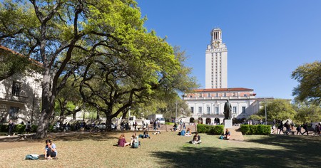Students reading on the grass in spring sunshine, The University of Texas at Austin, Texas, USA.