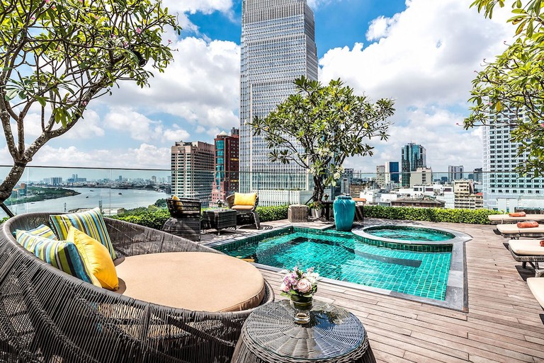 Rooftop pool and jacuzzi tub with stylish lounging chairs and lush greenery at Silverland Jolie Hotel & Spa in Ho Chi Minh City, Vietnam.