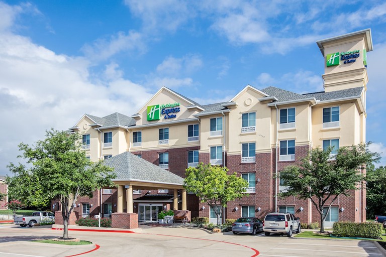 A double bed in a room with a lime green accent wall, a wooden desk and a TV at Holiday Inn Express Hotel & Suites Dallas Grand Prairie