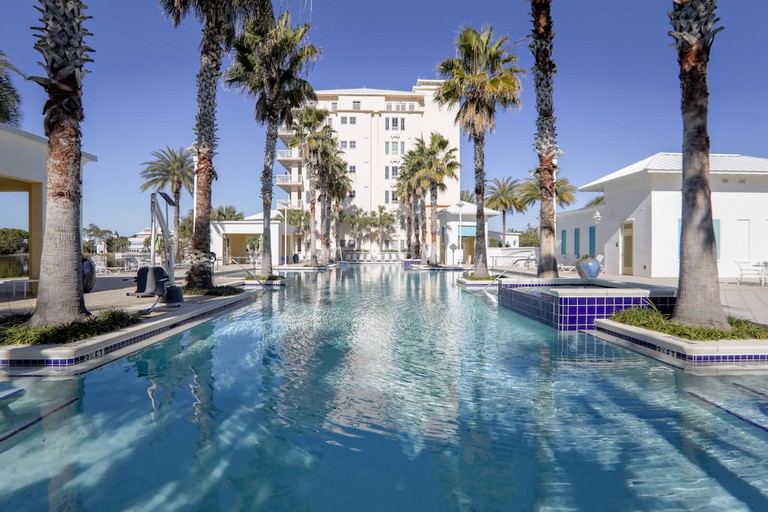 A long outdoor pool, complete with an accessible lift, flanked by palm trees at the Carillon Beach Resort Inn