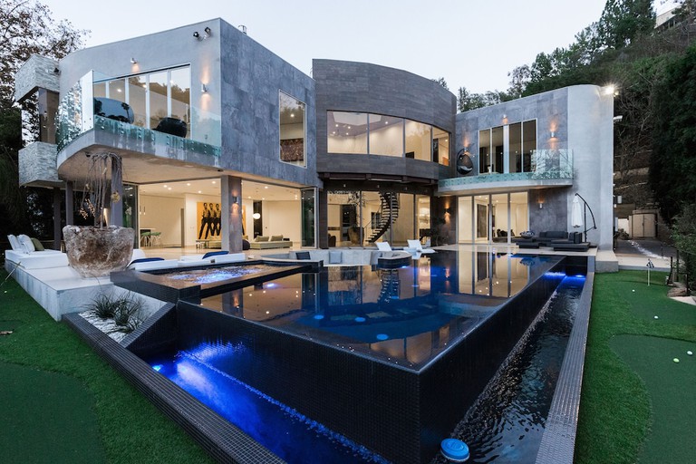 Stunning glass-and-stone modern architecture of Chantilly Estate in Bel Air seen from dark blue infinity pool area