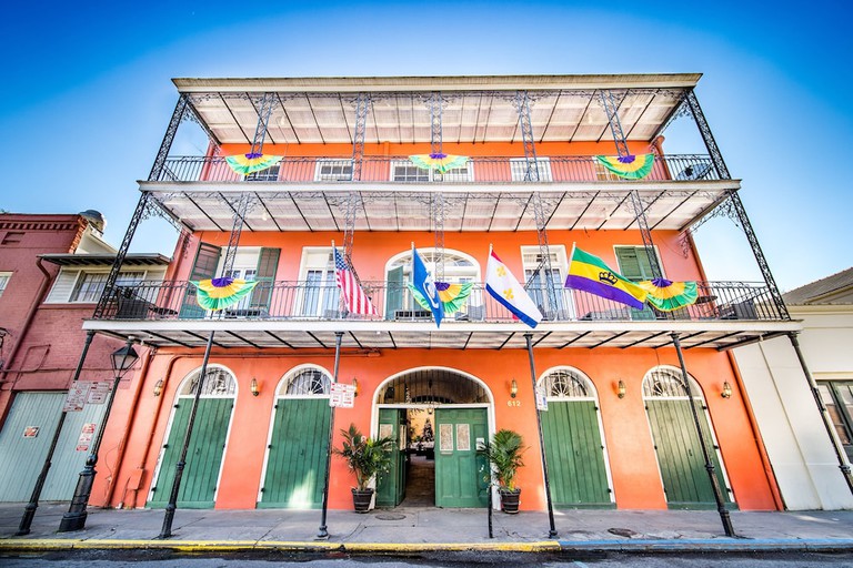 The classic New Orleans exterior of Saint Philip Residence with wrought iron balustrades and green wood shutters.