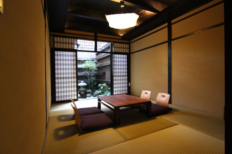 A low wooden table seating four people at Shoubuan Machiya Residence Inn, Kyoto, next to sliding shōji doors which open to a small private garden