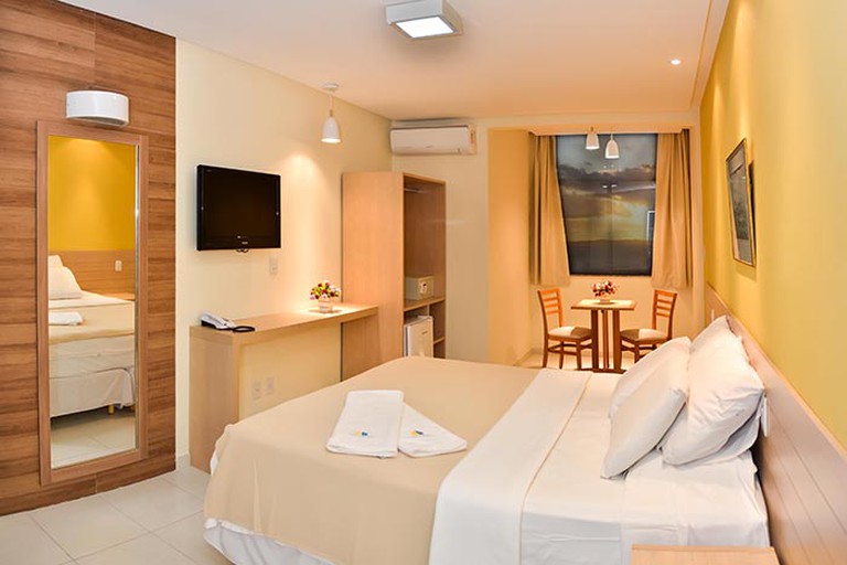Cream coloured double room with TV, table and mirror in the Hit Hotel