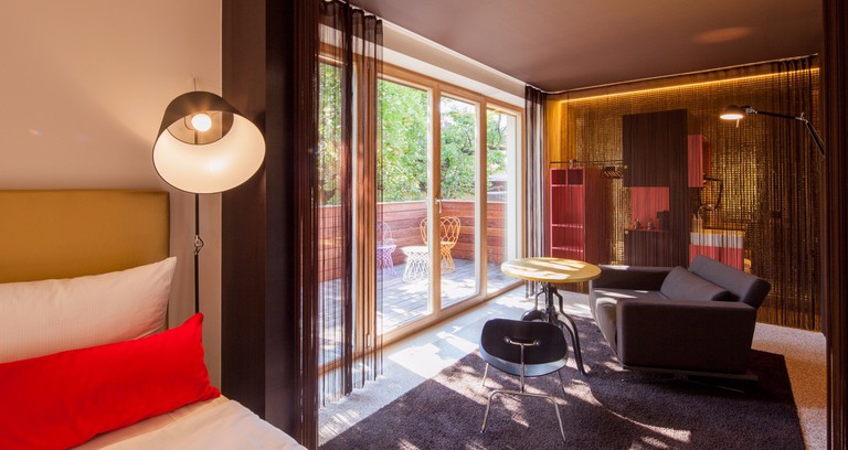A large double room with red and white furnishings and a wooden balcony at NALA individuellhotel, Innsbruck
