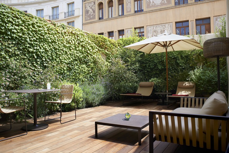 The courtyard of the Mercer Hotel Barcelona with wooden deck, living walls covered in plants, sunloungers, tables and relaxed seating