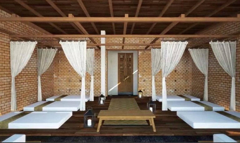 Six massage tables separated by four privacy curtains, plus a wooden bench in the middle of a room at Sanakeo Boutique & Spa