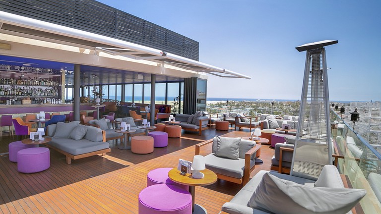 The rooftop bar and lounge with luxurious seating and panoramic city and ocean views at Bohemia Suites and Spa Hotel