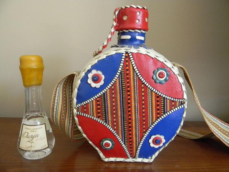 Bottle of Quince Rakija, beside Serbian traditional flask