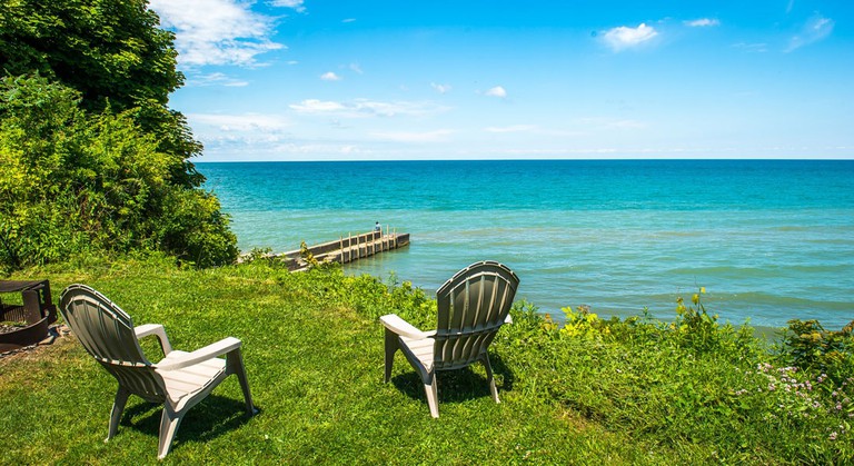 Lake view with lounger seats and blue skies from Virginia's Beach Lakefront Cottages & Camping