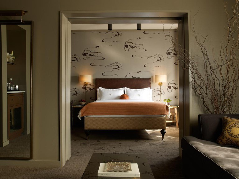 Warm and welcoming suite in earthy tones with separate bedroom featuring artist-drawn tan wallpaper at the Soho Grand Hotel