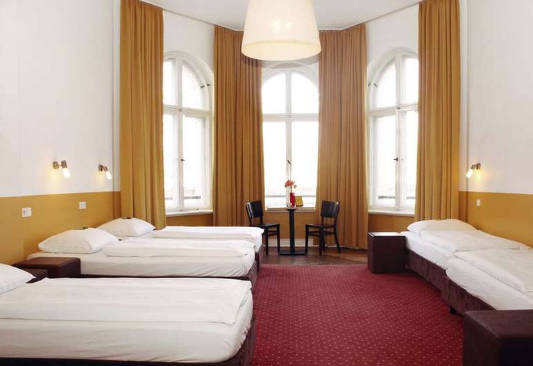 Several single beds and a table with two chairs in a dorm room at Grand Hostel Berlin Classic