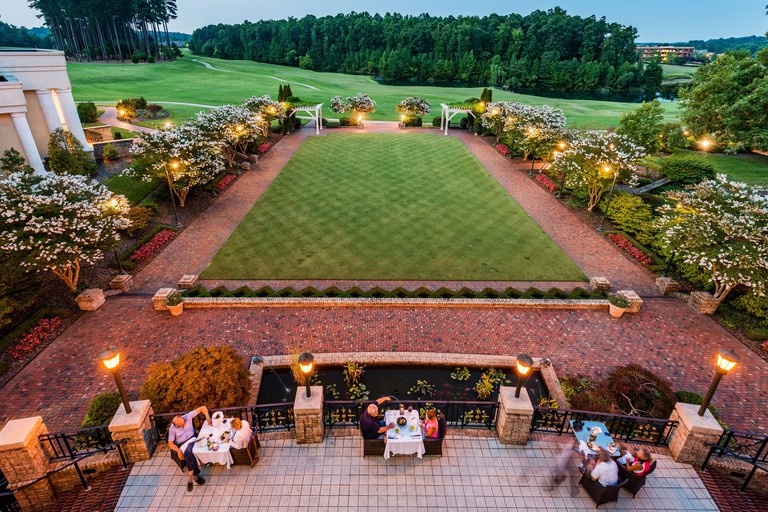 Three outdoor dining tables looking out over a perfectly manicured lawn and a golf course at Grandover Resort