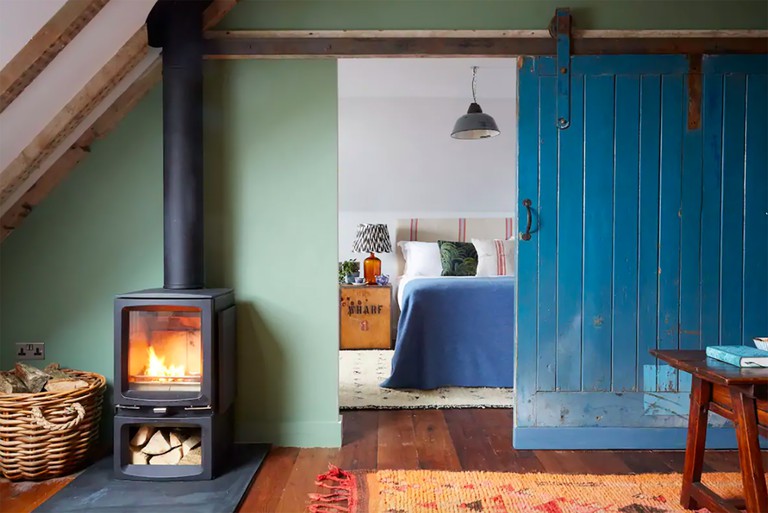Cosy apartment with log-burning stove, wood floors and large blue sliding farm door to bedroom at Artist Residence in Penzance