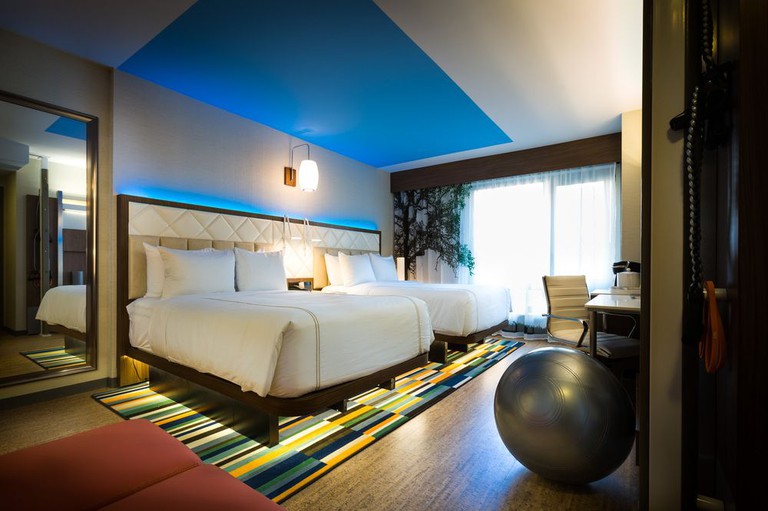Two beds, a colorful rug and an exercise ball in a hotel room at Even Hotel Times Square South
