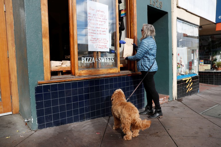 A customer picks up a bag of free pastries from the worker-owned Arizmendi bakery in the morning after the cooperative voted to temporarily shut its doors during day one of the citywide shelter in place order amid the outbreak of coronavirus disease (COVI