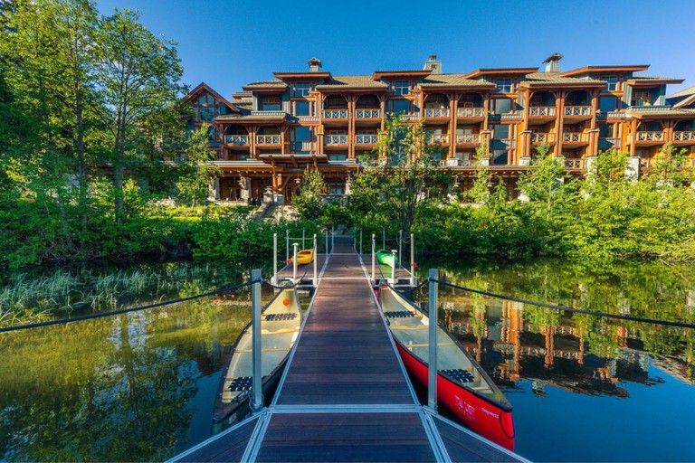 The exterior of Nita Lake Lodge, Whistler, as seen from the jetty by the lake, on which two rowing boats rest