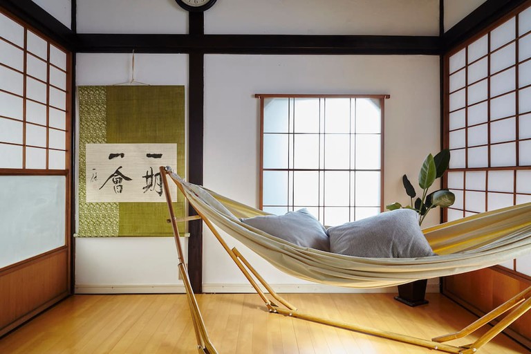 A hammock with pillows and a Japanese print on the wall in a room at Hidden 2Story Gem – Tokyo Hideaway