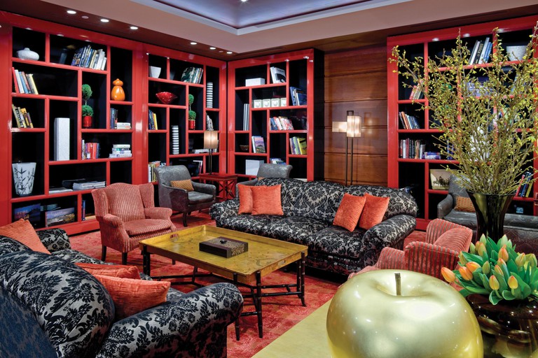 A dramatic lounge with silver-and-black sofas, red armchairs and red bookcases at the Bostonian Boston