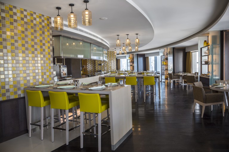 The bar and restaurant at Amman Rotana Hotel, furnished with modern decor in a yellow, grey and brown colour palette.