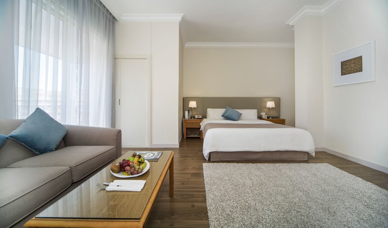 Spacious and modern double room at Al-Qasr Metropole Hotel in Amman, with a comfortable seating area and large windows offering lots of light.