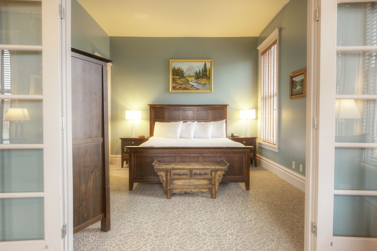 A classically styled room at the Montvale Hotel with dark wood furniture, tan patterned carpet, pale blue walls and landscape paintings