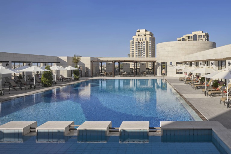 The open-air rooftop pool and sun-lounging terrace at the Sheraton Hotel in Amman.