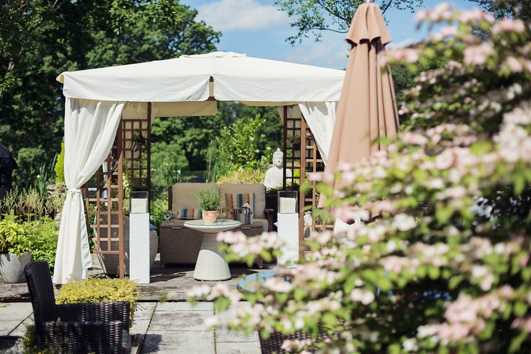 The flourishing garden at the Gilpin Hotel has a wooden gazebo covered by canvas, under which is an intimate seating space