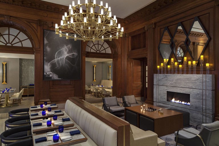 Chic Amuse brasserie with wood paneling, chandelier and fireplace at Le Méridien in Philadelphia