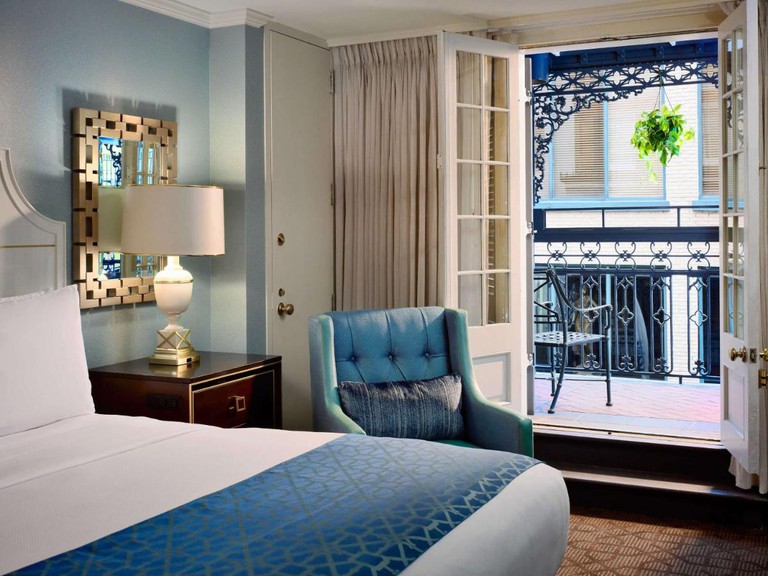 A double bed in the foreground with open doors to a balcony at Royal Sonesta New Orleans