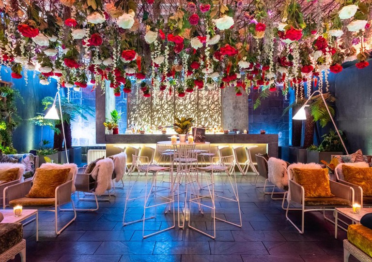 Trendy bar area at the South Place Hotel, with flowers hanging from the ceiling and modern chairs