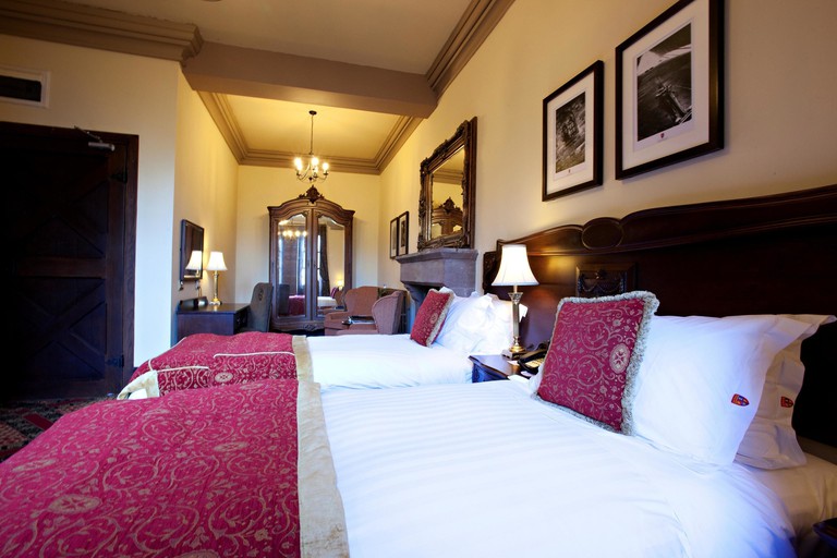 Twin room at Peckforton Castle has antique decor and plush furnishings