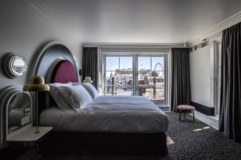 Henrietta Hotel room with city view, pattern carpet and quirky furniture including a footstool