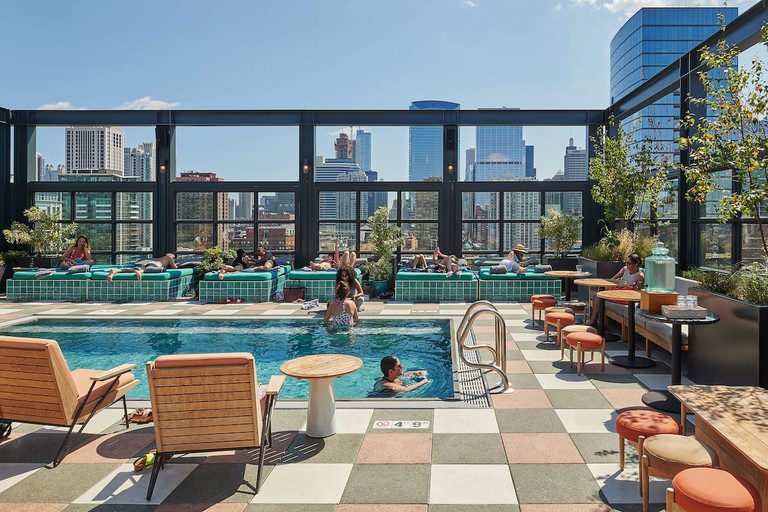 The rooftop pool at the Hoxton, with guests swimming and the Chicago skyline as a backdrop