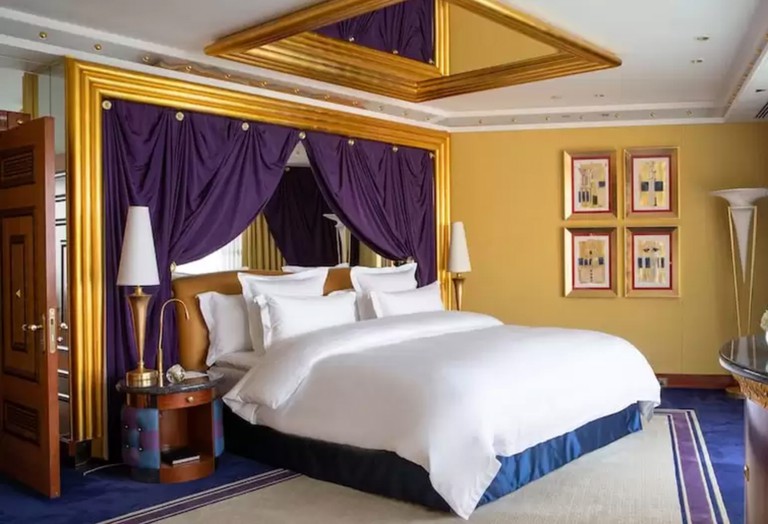 Sumptuous king bedroom with purple curtains, mirror on ceiling and royal blue carpet at Burj Al Arab, Dubai