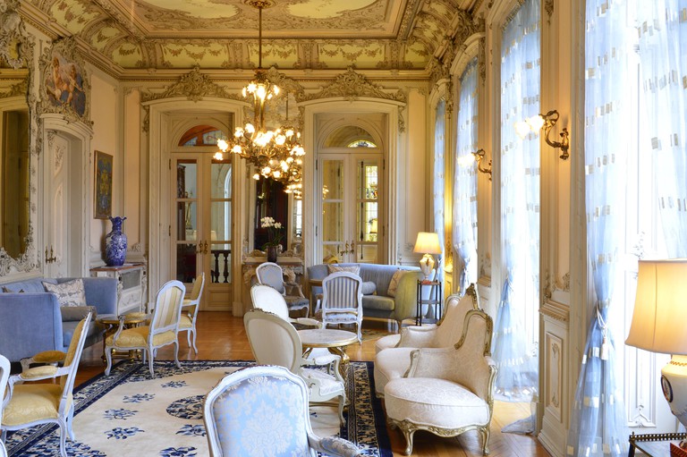 The grand dining hall at Pestana Palace Lisboa is filled with French-style furniture, tall detailed ceilings and unique art