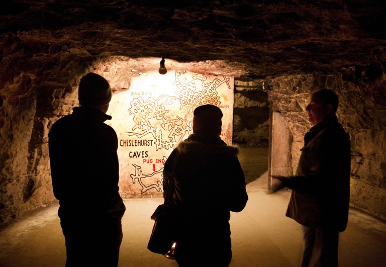 Two people on a tour of Chislehurst Caves are shown a map by their guide