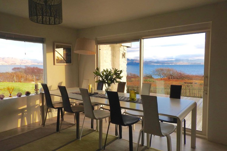 A light dining area with a table, chairs and large windows at KnoydArt Bed and Breakfast