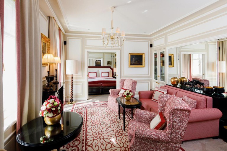 A luxurious suite, including a living room and bedroom, with red, white and gold decor in the Hotel Sacher Salzburg in Austria