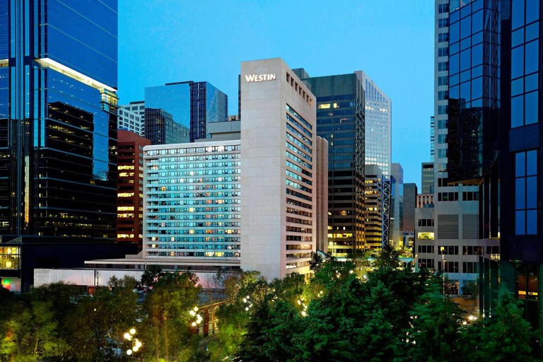 Exterior of the Westin Calgary at night, surrounded by other city skyscrapers and trees