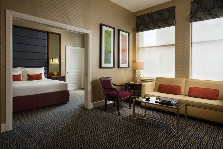 Large double bedroom at Kimpton Hotel Monaco Baltimore Inner Harbor with checked gold wallpaper, white linen and dark carpet