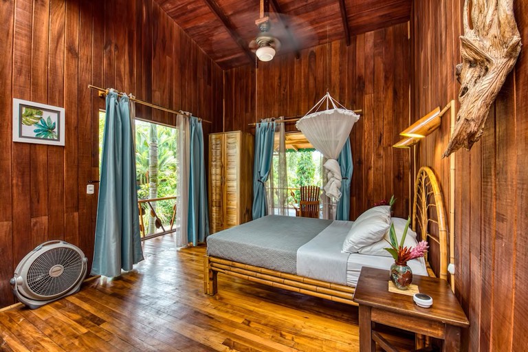 A bed in a wood-panelled room with a balcony at Hotel Banana Azul