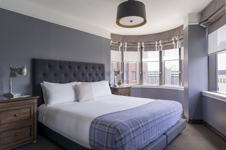 A light bedroom at The Boxer Hotel, with large windows, bedside tables and reading lights