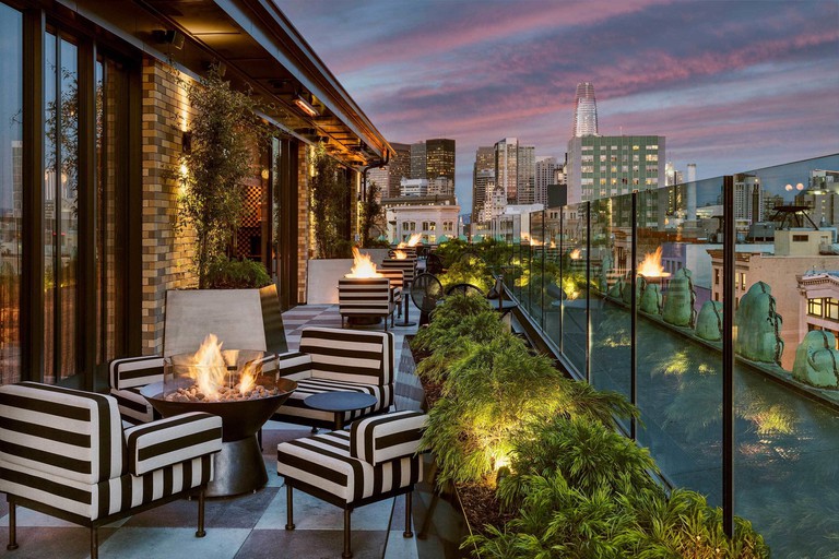 Rooftop lounge area with white and black striped chairs arranged around fire pits at San Francisco Proper Hotel, San Francisco