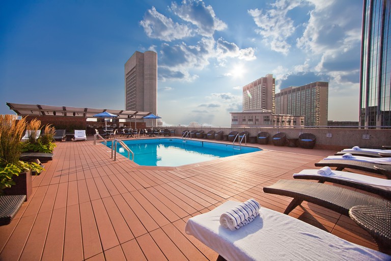 A rooftop outdoor pool at The Colonnade Hotel Back Bay, Boston, with wooden decking, sun loungers and city views