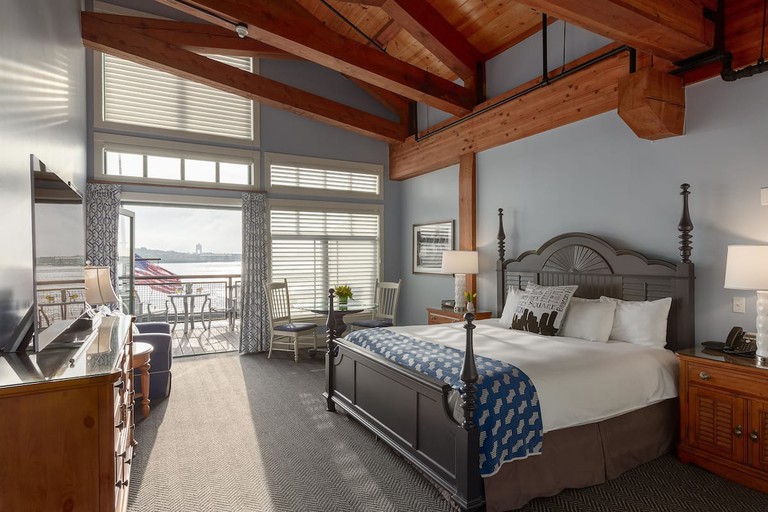 Chic king room with high, exposed-beam ceilings, wood furnishings and harbor-view deck at Boston Yacht Haven Inn and Marina