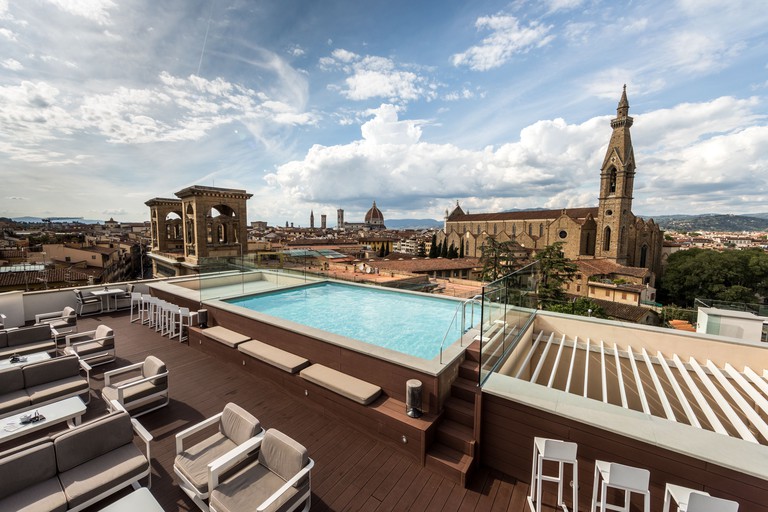 A small but stylish pool with outdoor seating looking over the historic buildings of Florence at Plaza Hotel Lucchesi