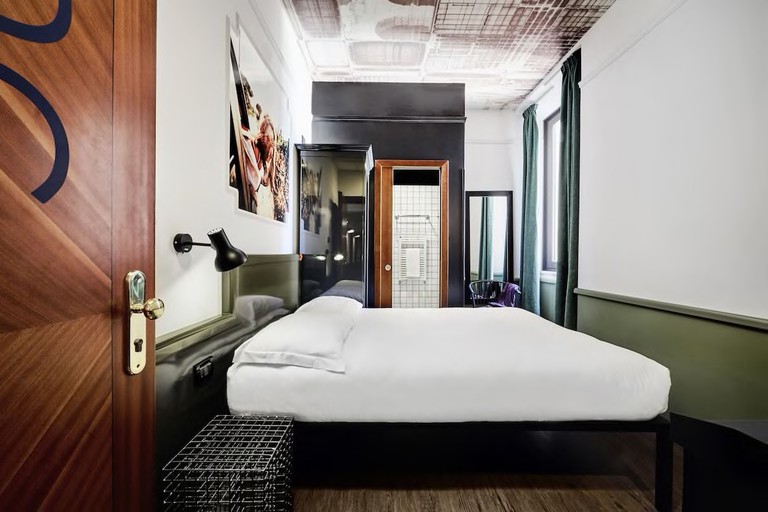 A bed and wardrobe in a stylish hotel room with a bathroom at Generator Rome