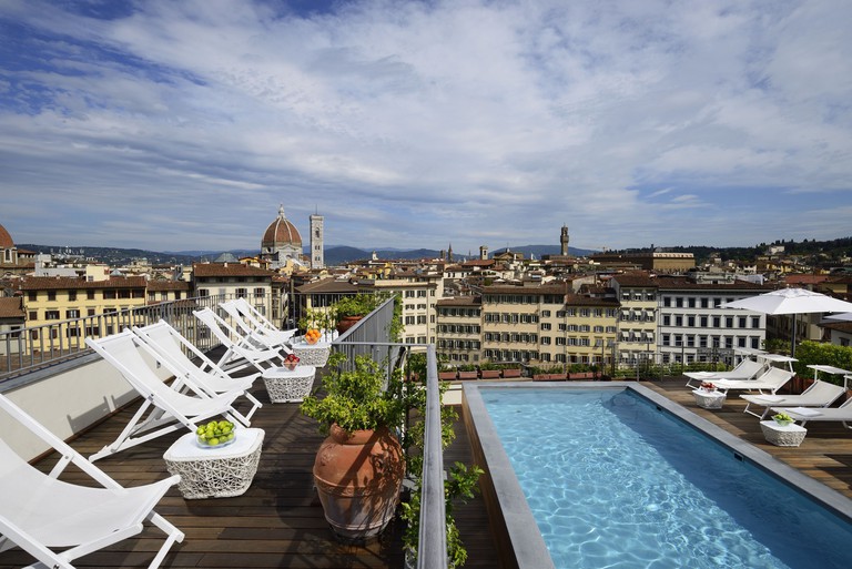 A small rooftop pool with relaxing chairs looking over the Florence skyline at Grand Hotel Minerva