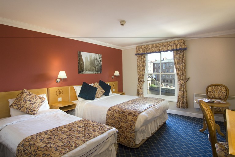 Room at the Queen's Hotel with twin beds, blue carpet and floral curtains and throws